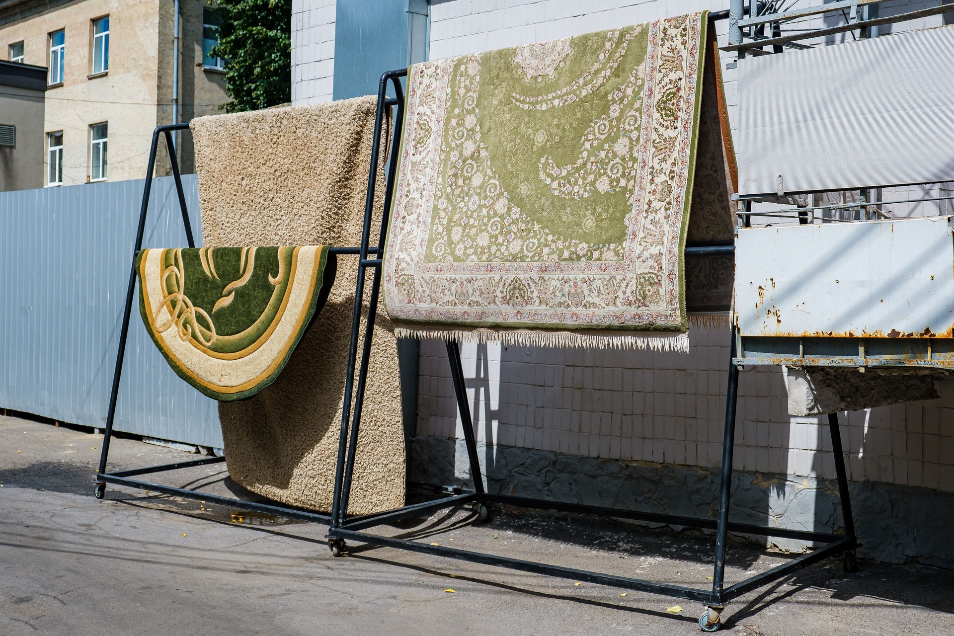 Different carpets hanging on rack outdoors. Professional carpet cleaning and drying